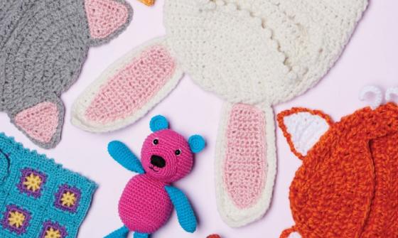 A flat lay of several different crocheted children's items including toys and clothing.
