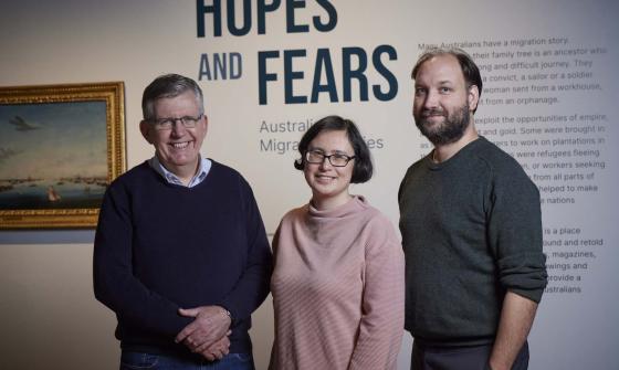 Two men and one woman standing and smiling at the beginning of the 'Hopes and Fears: Australian Migration Stories' exhibition at the Library