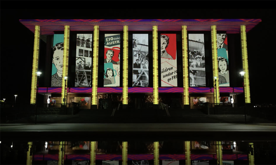 The National Library of Australia building at dusk, lit up with colourful projections.