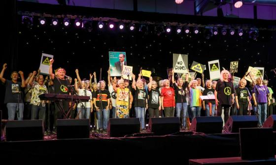 A crowd of people on a stage holding placards.