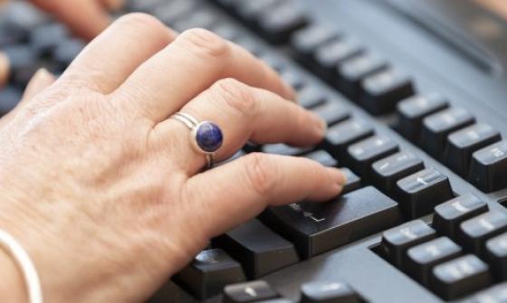 Close-up of hands typing on a black computer keyboard
