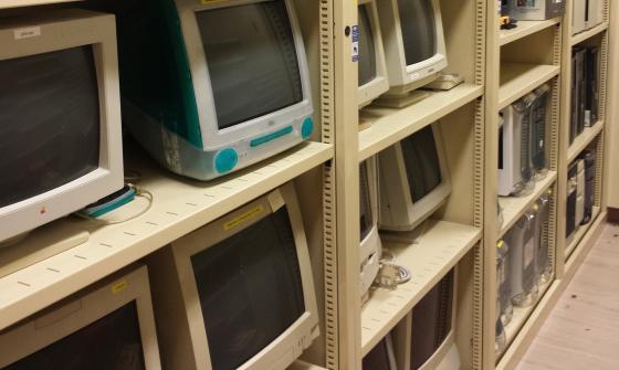 Old fashioned computers and other machines sit on tall beige shelves