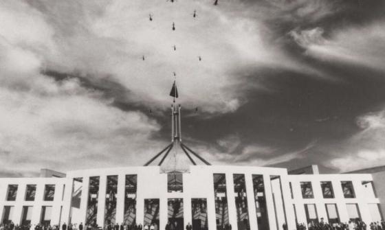 Helicopter flypast above the flagpole of Parliament House, with a crowd gathered below on the steps, Queen visible in the lower right, Canberra, 1988