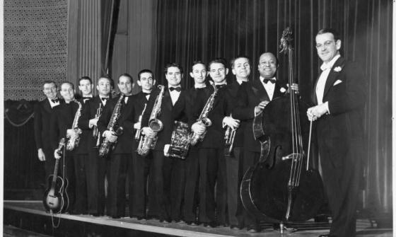 A row of men in concert dress holding musical instruments