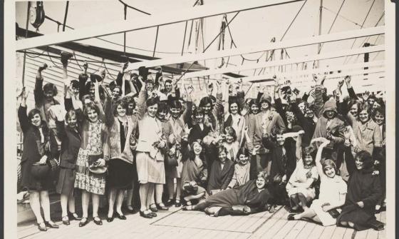 Black and white photo of British migrant women waving on the deck of a ship