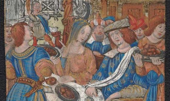 A colourful image of a feast. Men and women are dressed in colourful clothes. There is a table with a white tablecloth. There is a plate of food on the table.