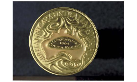A photo of a gold medal showing a map of Australia surrounded by the words Britannica Australia Awards. In the middle of the map of Australia are the engraved words 'Literature, 1964, Judith Wright'.