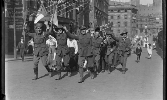 photo of soldiers waving flags and cheering as they walk down a street