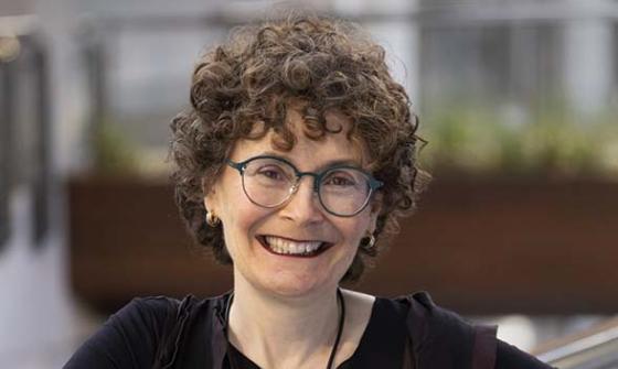 woman leaning against glass partition smiling at camera