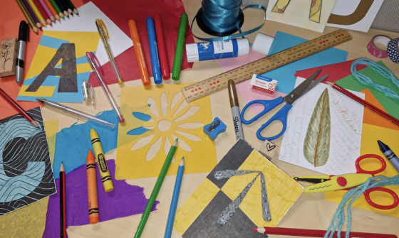 Colourful arts and crafts supplies, including markers, crayons, pencils, scissors, tissue paper, cardboard, wool and ribbon.