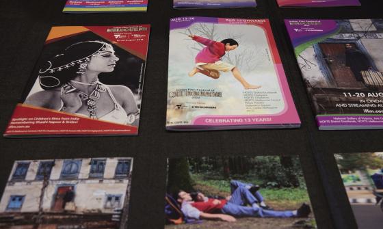 Brochures from various years of the Indian Film Festival of Melbourne on a black surface