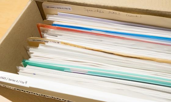 A cardboard box full of white paper separated by coloured plastic dividers