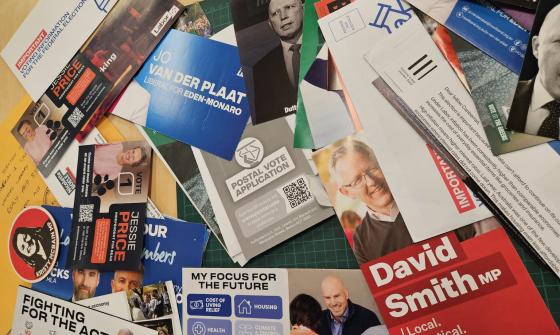 A variety of recently donated 2025 election campaign material laid out on a table. 