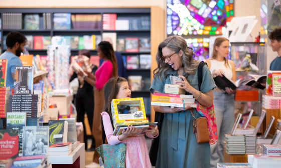 A woman and child holding books and gifts in the National Library Bookshop.
