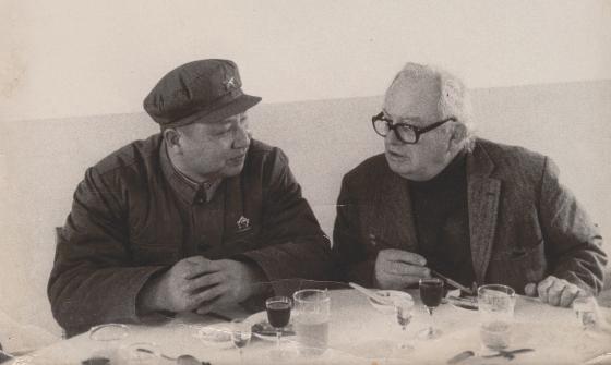 Two men, Wilfred Burchett and Mao Zedong sitting at a small table and talking over a meal