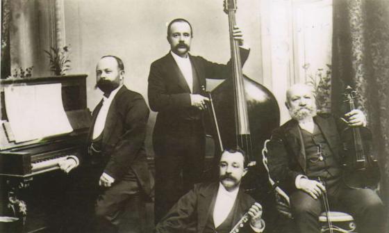 Four men posing in dress suits holding musical instruments.