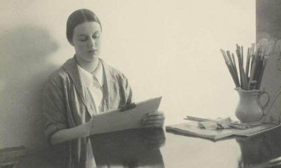 Portrait of Nora Heysen sitting at a desk and painting