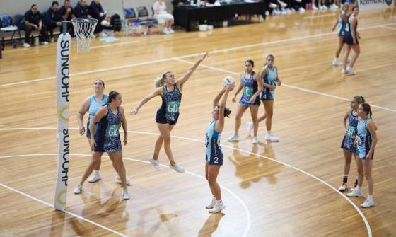 Action shot during a netball game as a women jumps up to prevent another from scoring