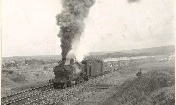 A black and white photograph showing a steam train on a track