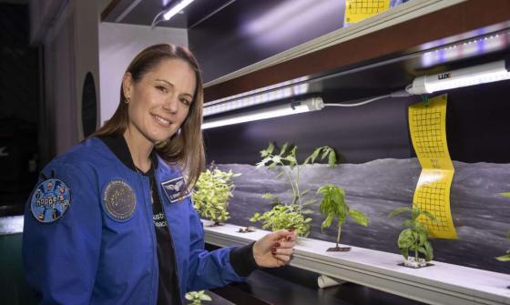 Katherine Bennell-Pegg standing next to plant samples in a lab