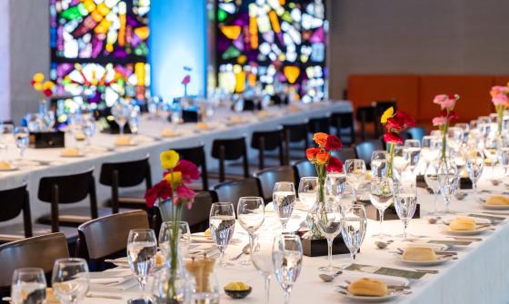 Bookplate cafe set up with long tables with white tablecloths, flowers, glasses and bread rolls