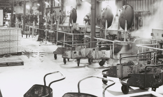 Black and white photo of a factory floor lined with steaming pressure cookers.