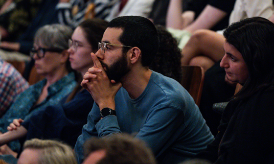 An audience watching a performance in a theatre with a focused expression