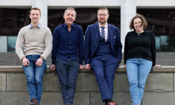 Three men and one woman standing in front og the National Library building