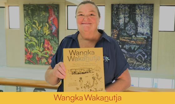 Rebecca Bateman, holding the NLA Publication, Wangka Wakanutja, in the National Library of Australia