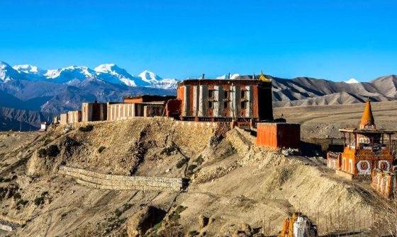 A monastery and other buildings with mountains with snow on top in the background