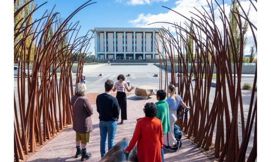 Sita Sargeant standing before a group across the road of the front of the National Library of Australia