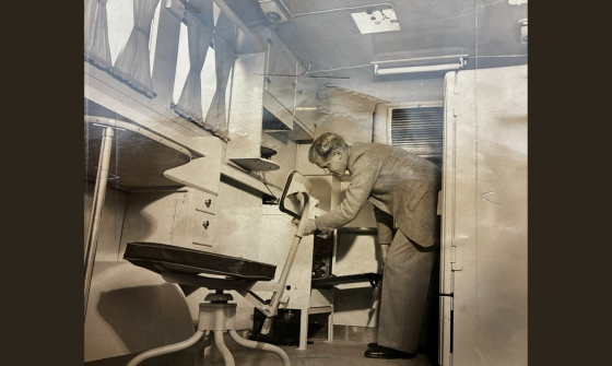 A sepia photograph of a man opening a drawer in a caravan