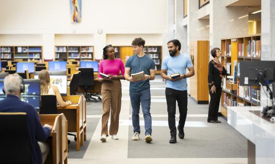 Three individuals walking through the main reading rooms