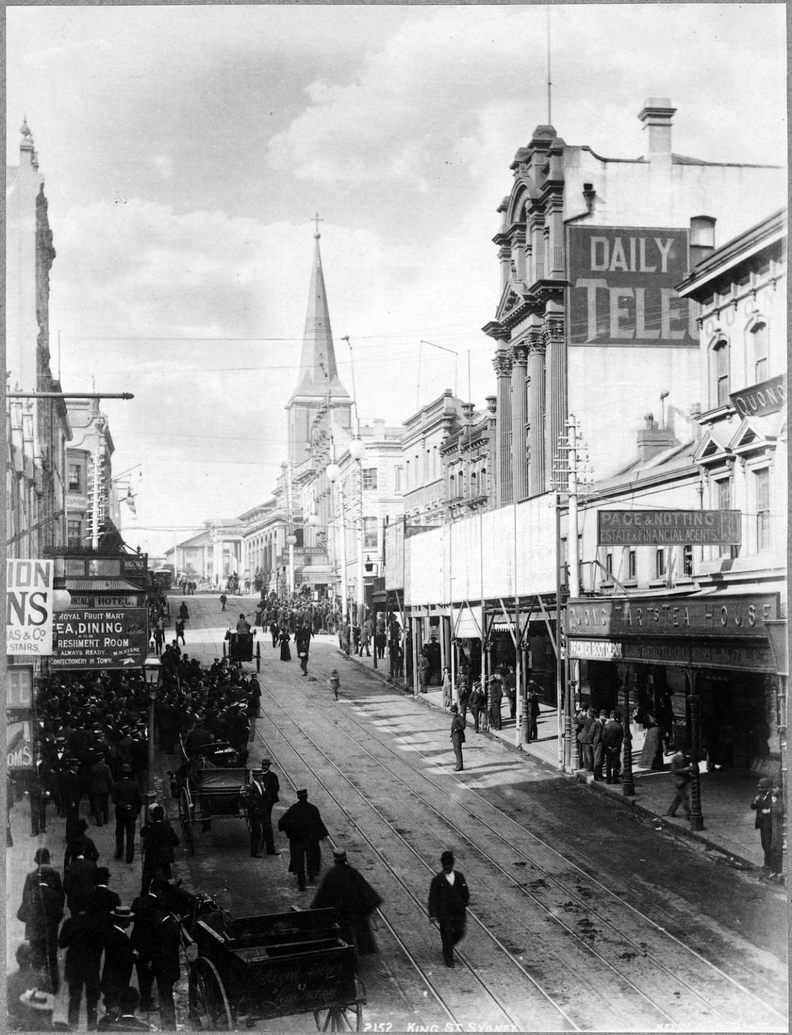 Building-lined street with many people and carts moving down the side