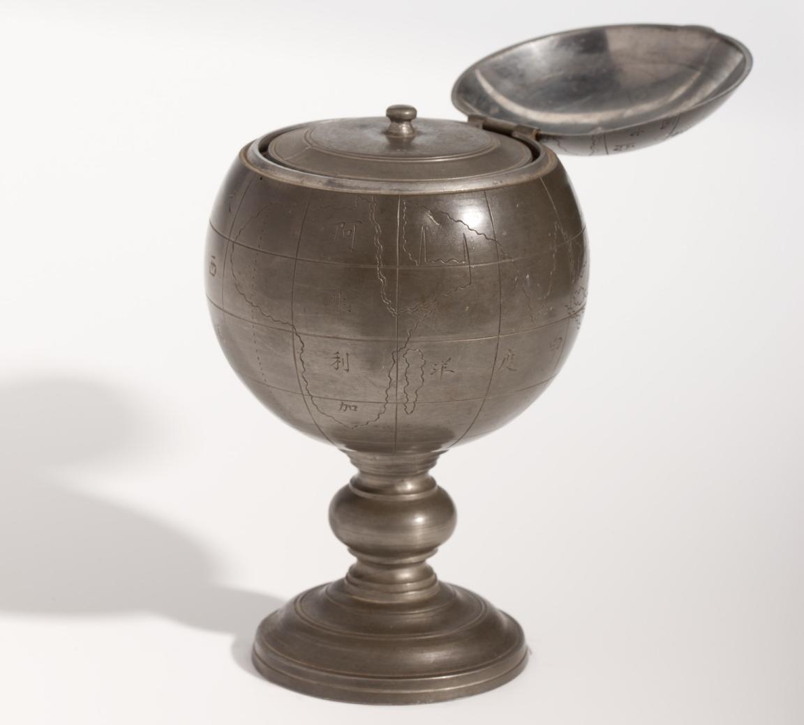 Round pewter tea caddy with a map engraved on it and the lid open