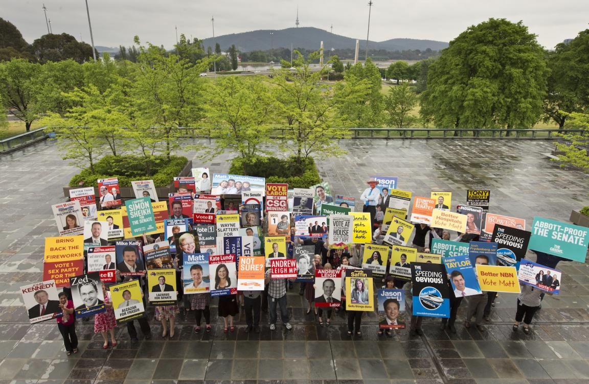 People standing holding colourful corflutes/posters from the 2013 election