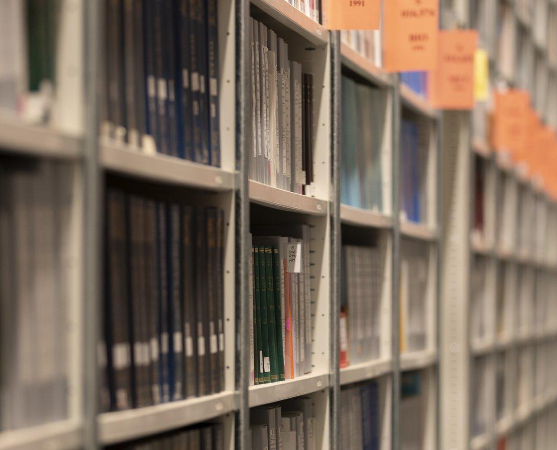 Long shelves of books and other print material with regular orange signs