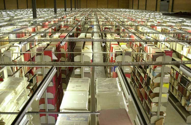 Rows of shelves containing books, papers, and other items