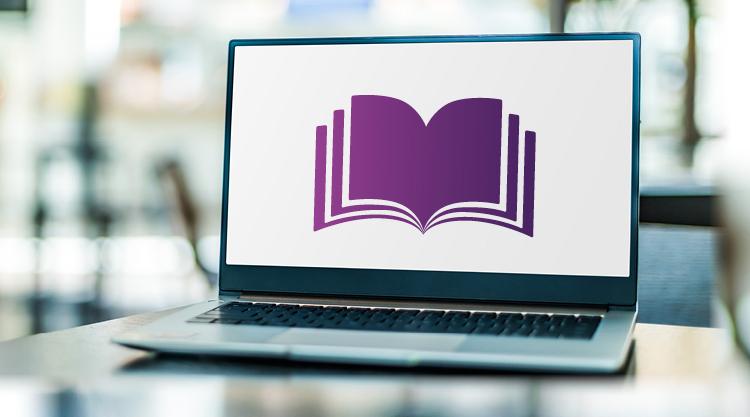 A laptop sitting on a desk with a stylised purple book on the screen.