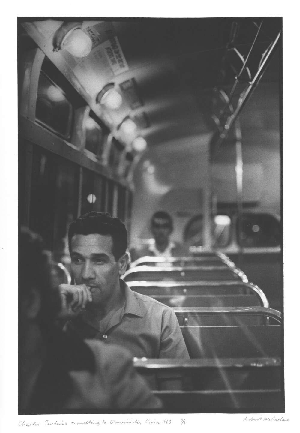 A black and white photo of a man sitting on a train