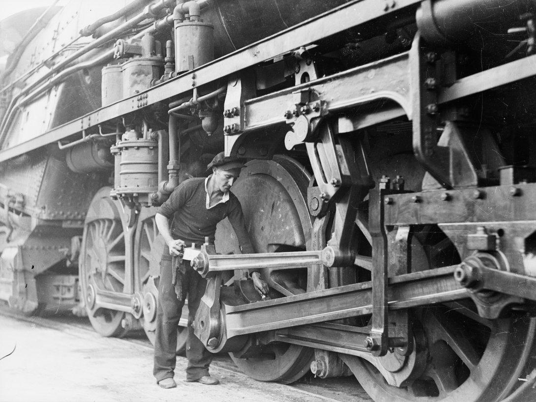 Man oiling part of a large steam train
