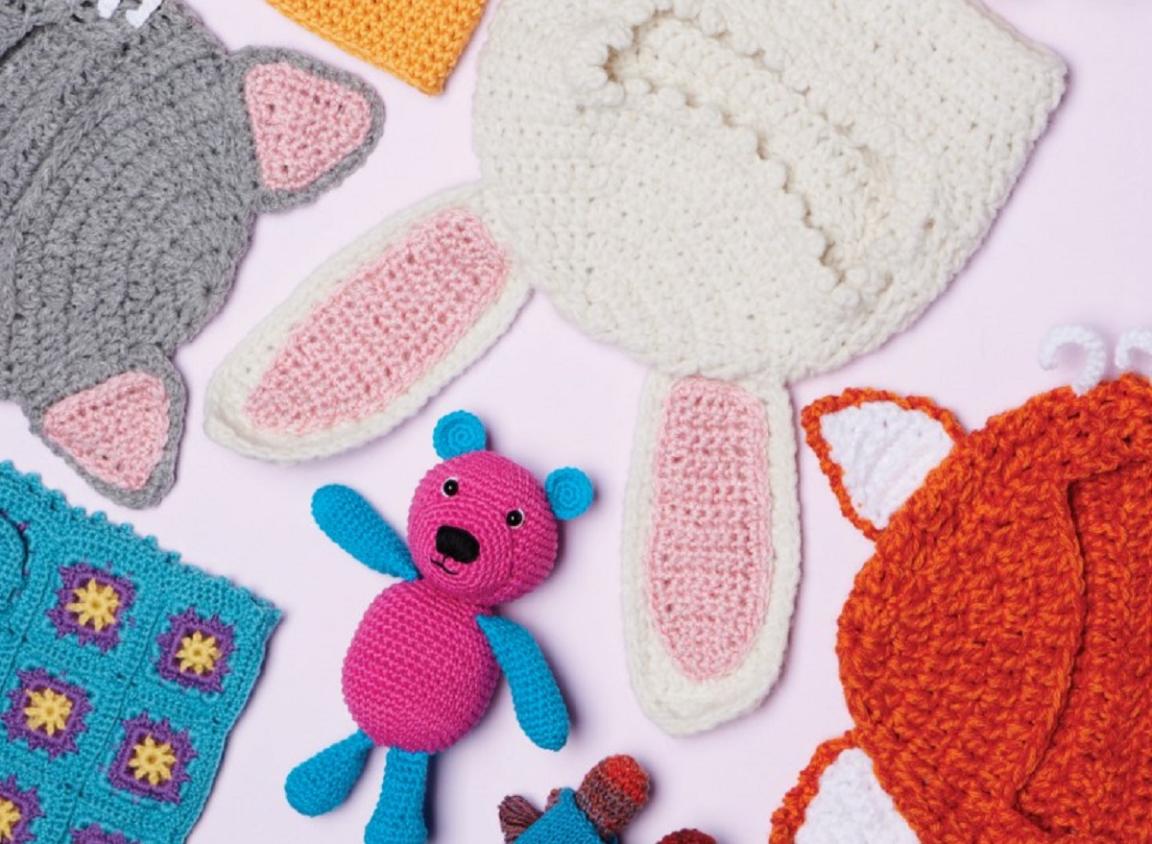 A flat lay of several different crocheted children's items including toys and clothing.