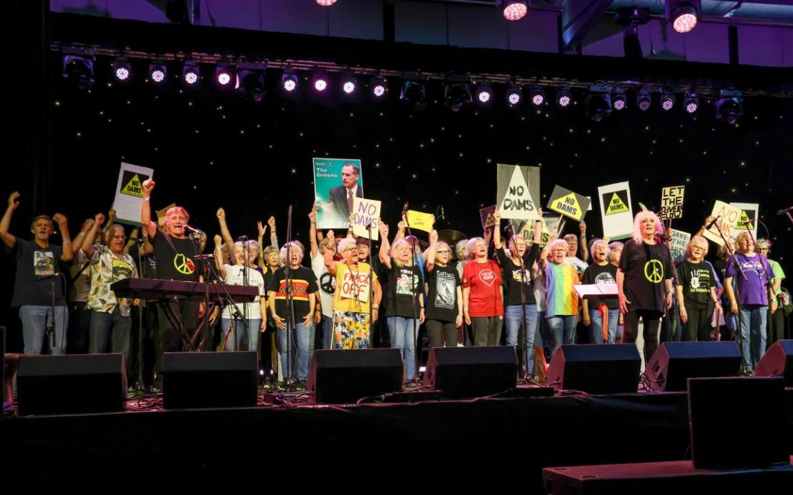 A crowd of people on a stage holding placards.