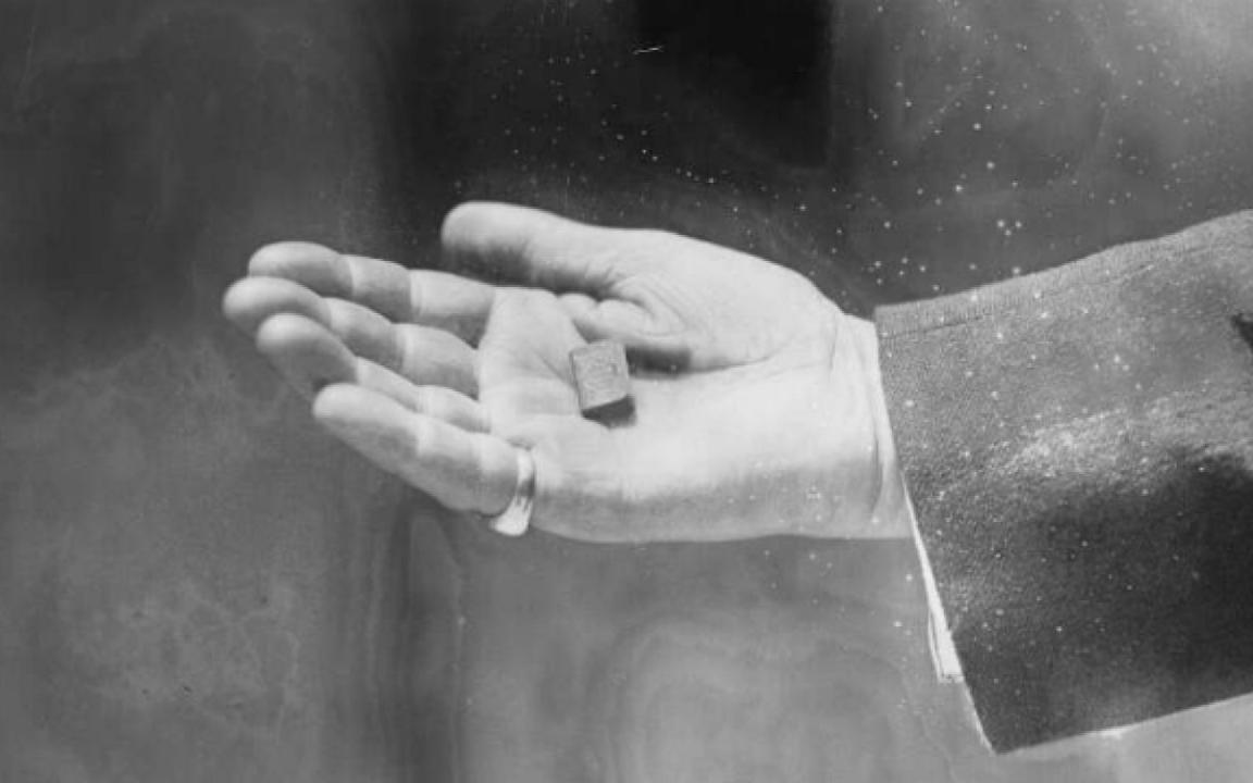 A miniature book sitting in a mans hand