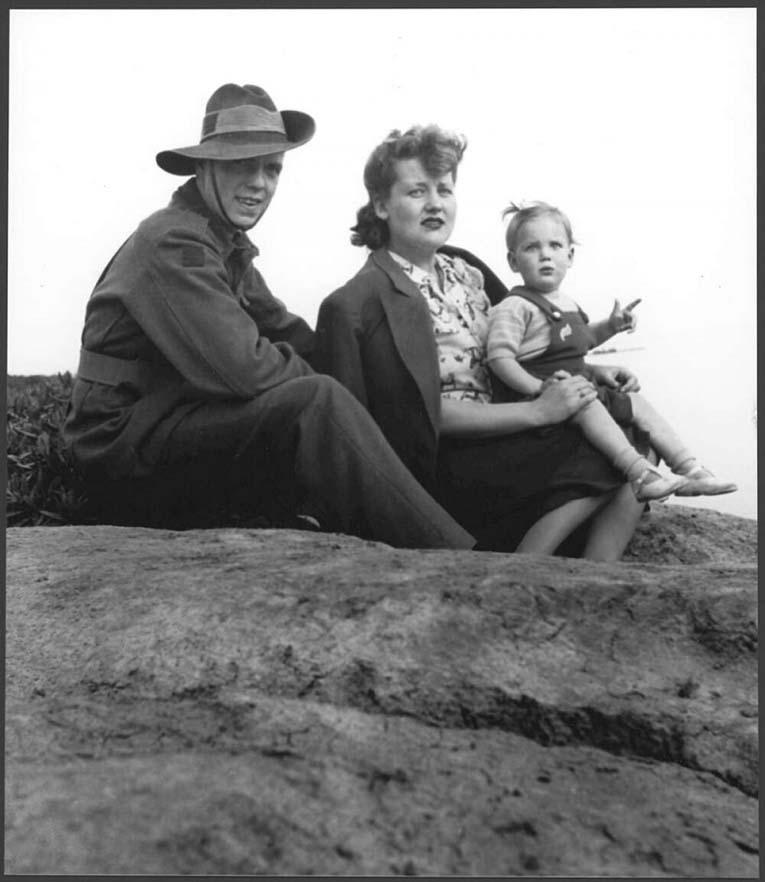 A man, woman, and child sit on the ground, looking at the camera