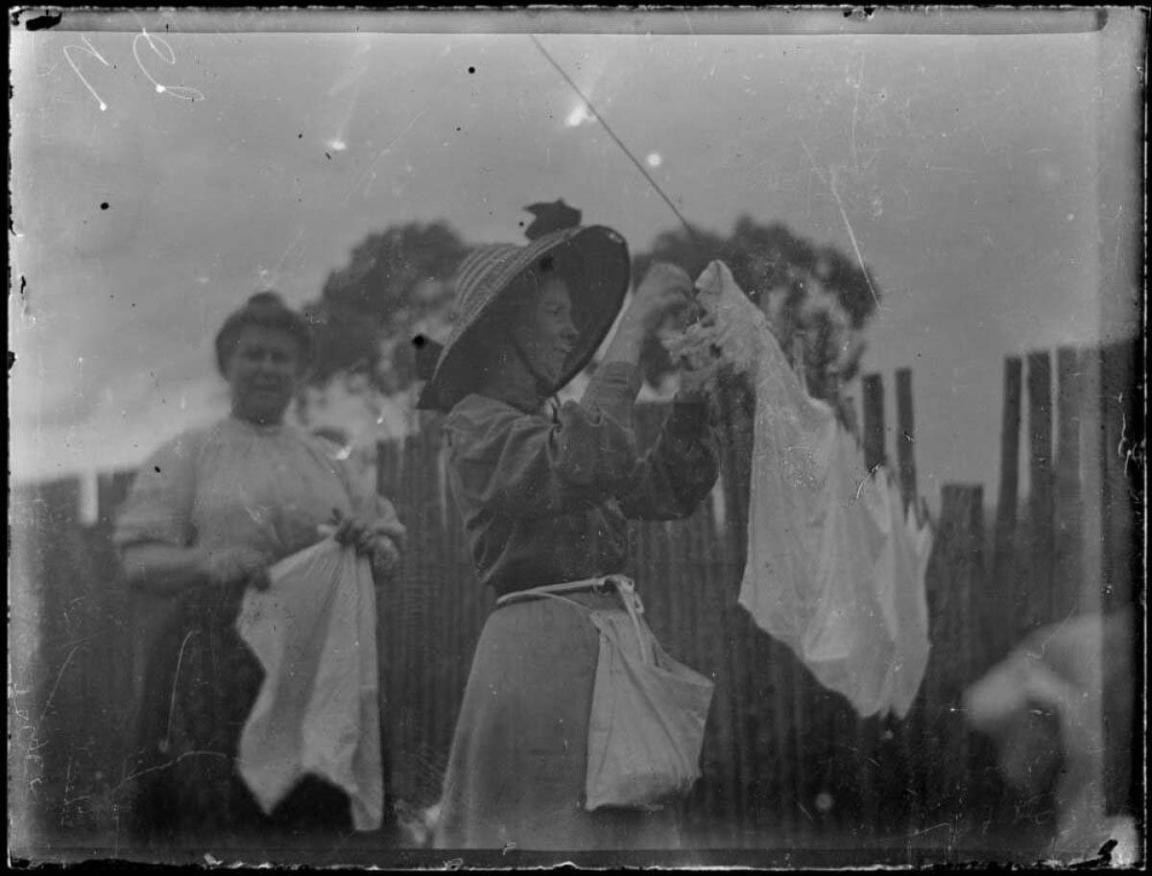 black and white photograph of two women hanging washing on a clothes line