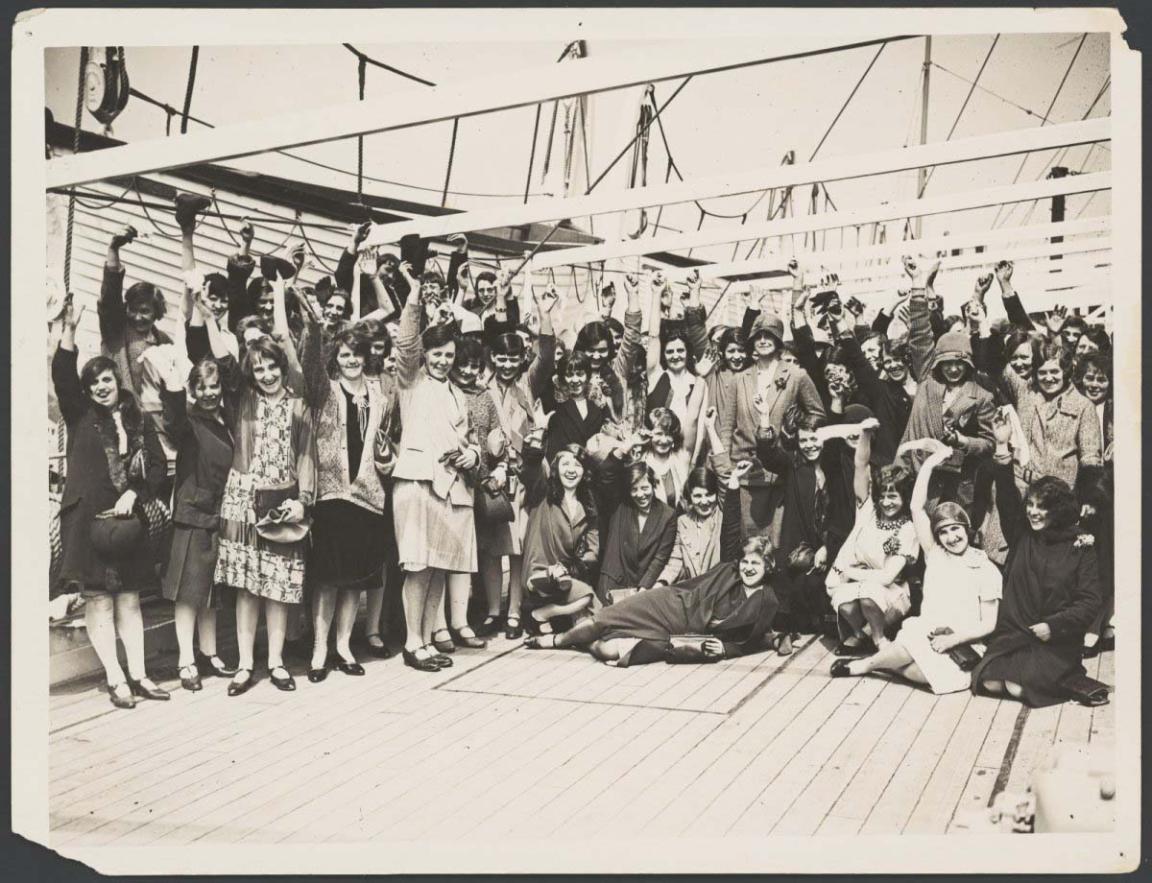 Black and white photo of British migrant women waving on the deck of a ship