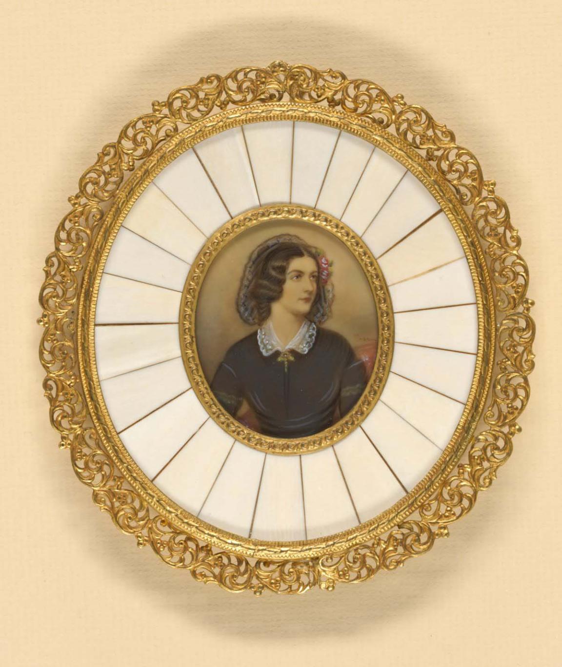 A round brooch with a gold filigree outer ring. White ivory inlay and a portrait of a lady dressed in a black dress.