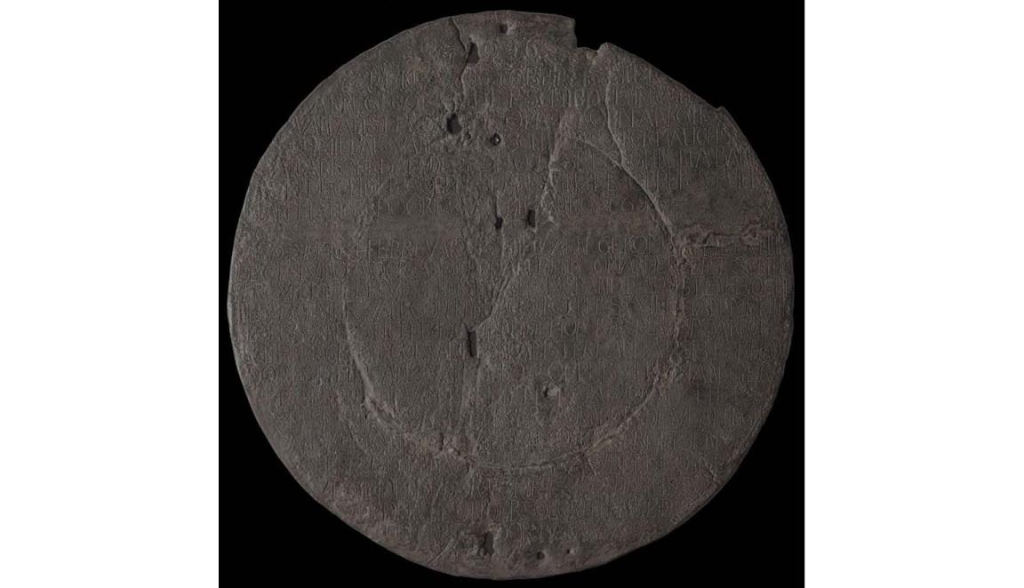 Image of a pock marked copper plate with writing inscribed across it from top to bottom.