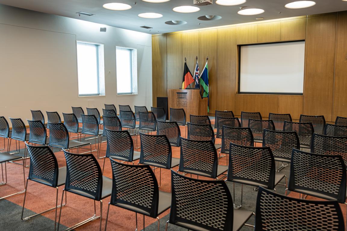 Chairs lined up in rows facing a projector screen and lectern in the Conference Room